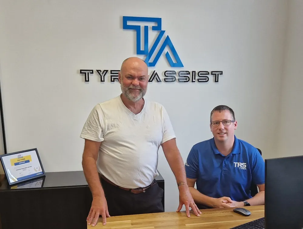 Two employes from TRS stood in front of the Tyre Assist logo