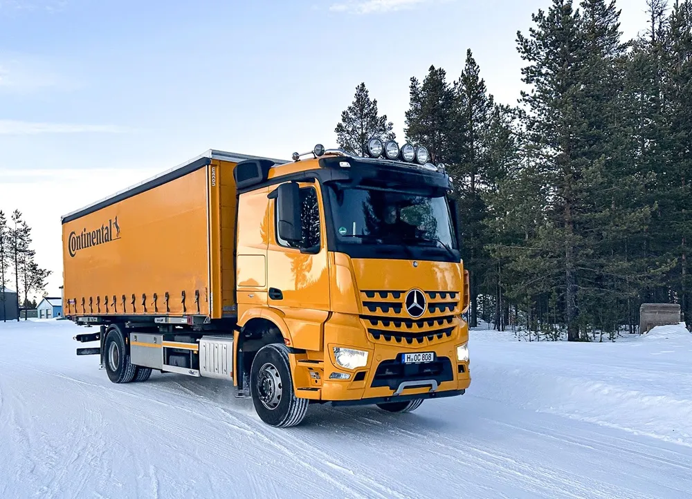 Continental Truck in Yellow on a snowy road with trees in the background