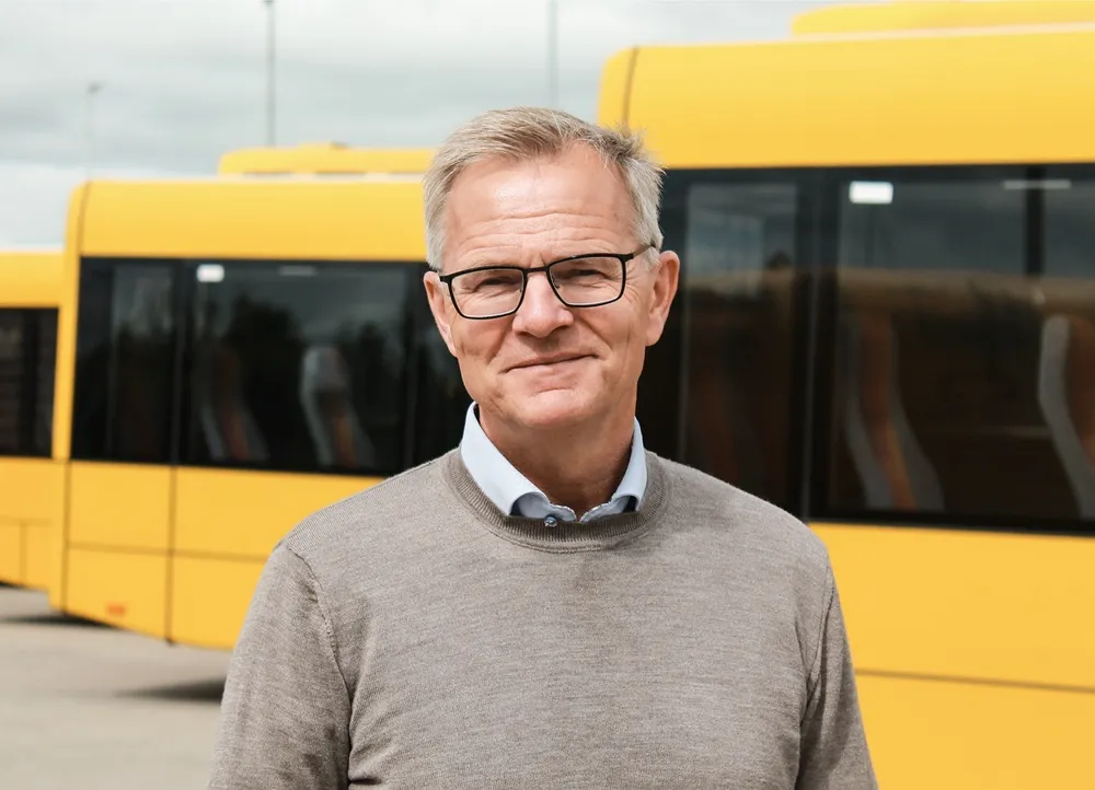 Image of Hans Jørgen Østergaard, Managing Director at AarBus in front of yellow buses