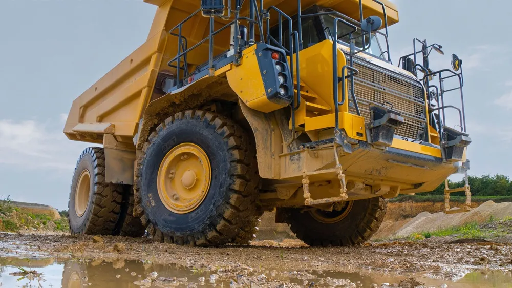 Image of a yellow dump truck on a wet quarry, taken from a below angle looking up